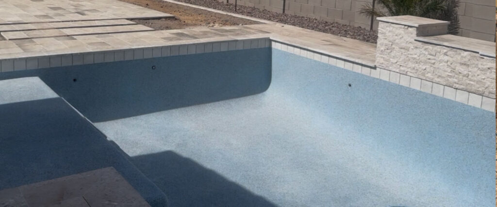 Pool plasterer insurance Arizona — pebble finish pool with waterline tile and travertine deck
